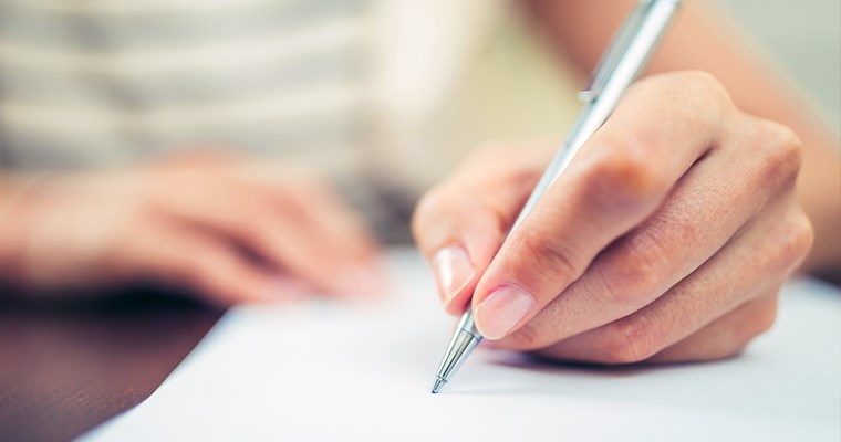 हाथ पकड़े पेन से कागज पर लिखना